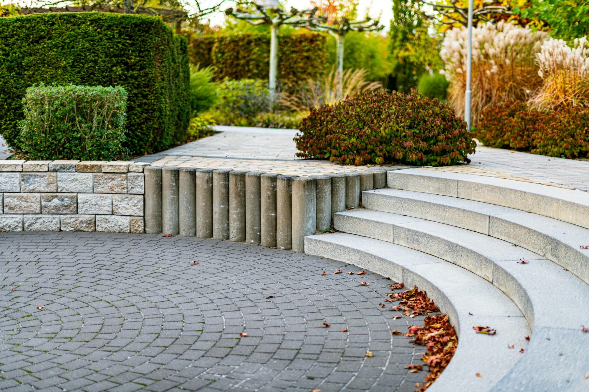 Segmental retaining wall and paved terrace built into a re-graded slope, with curved stone steps and planting above.